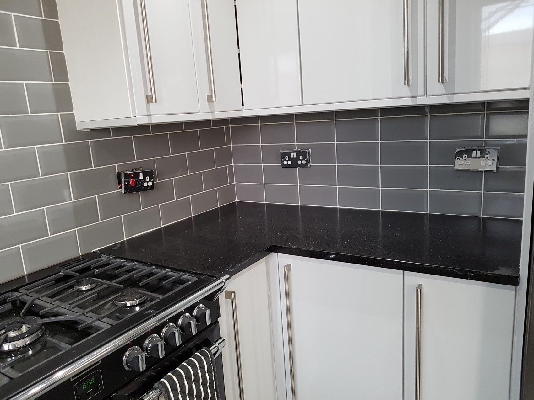 Grey metro tiles behind a black worktop
